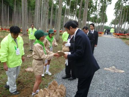 緑の少年団から森林土壌生成促進材を受けとる